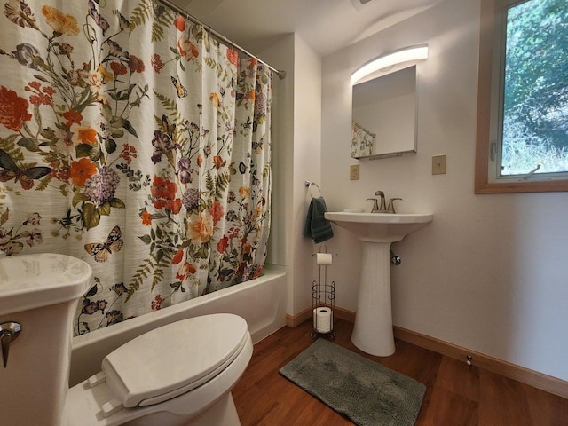 bathroom with wood-type flooring, shower / bath combo, and toilet