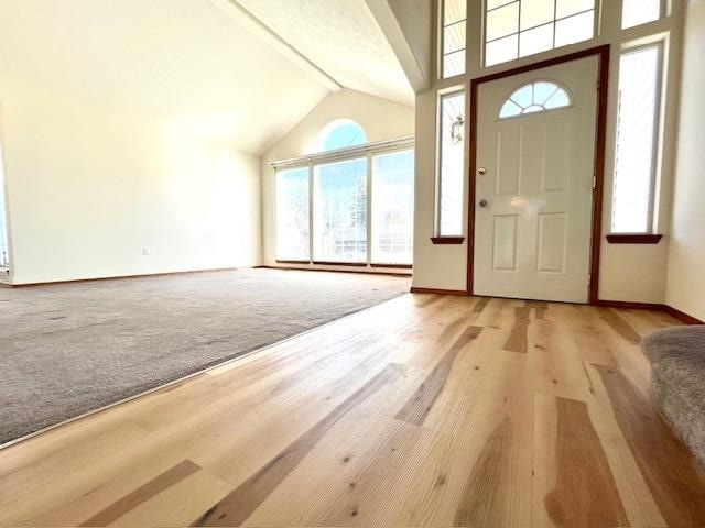 foyer entrance featuring vaulted ceiling with beams and light hardwood / wood-style flooring