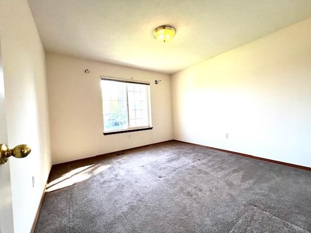 unfurnished room with dark colored carpet