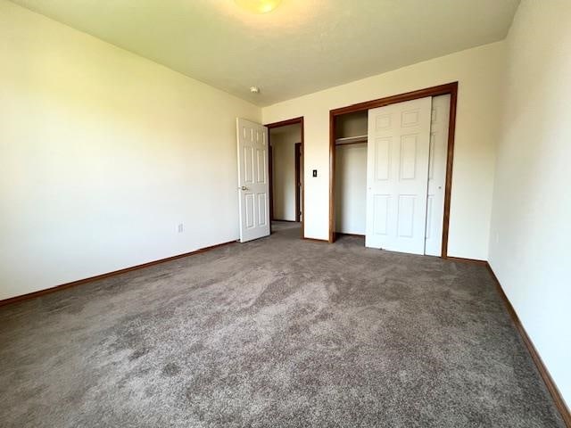 unfurnished bedroom featuring a closet and dark colored carpet