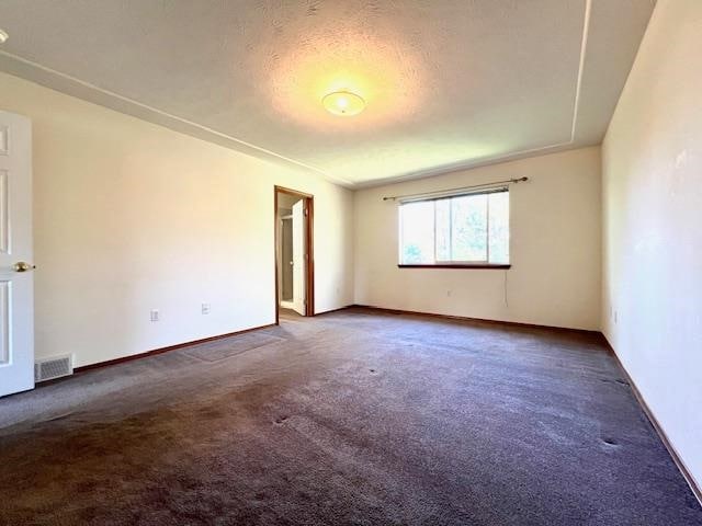 carpeted empty room featuring a textured ceiling