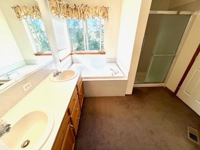 bathroom featuring plus walk in shower, plenty of natural light, and vanity