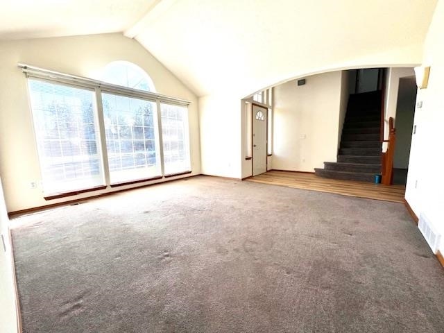 unfurnished living room featuring carpet floors and lofted ceiling with beams