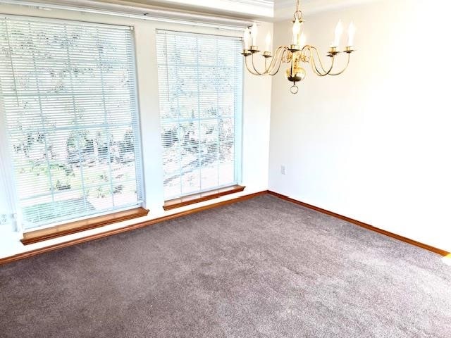 carpeted spare room with an inviting chandelier and ornamental molding