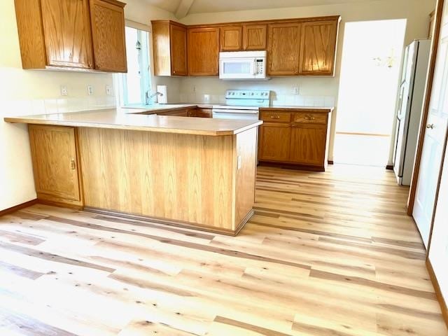 kitchen featuring white appliances, light hardwood / wood-style flooring, and kitchen peninsula