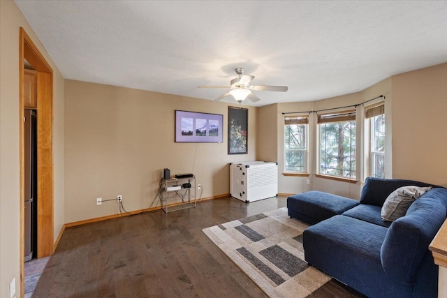 living room with a textured ceiling, dark wood-type flooring, and ceiling fan