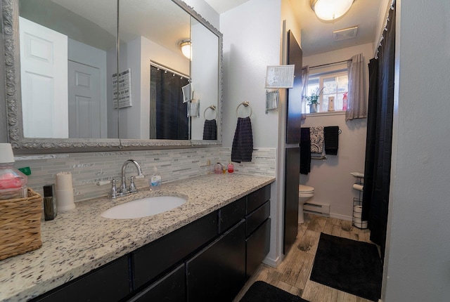 bathroom with backsplash, vanity, wood-type flooring, a baseboard radiator, and toilet