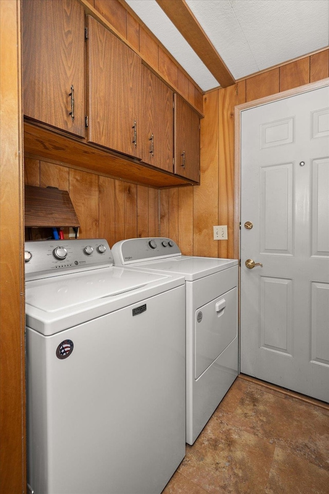 clothes washing area featuring cabinets, wood walls, a textured ceiling, and independent washer and dryer