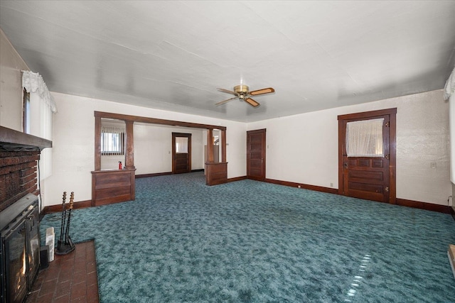 unfurnished living room with dark carpet, ceiling fan, and a brick fireplace