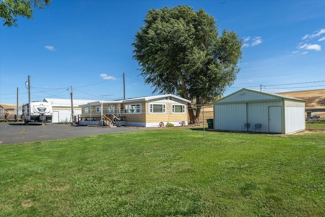 rear view of property featuring a lawn and a shed