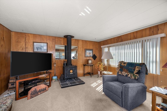 carpeted living room with a wood stove and wooden walls