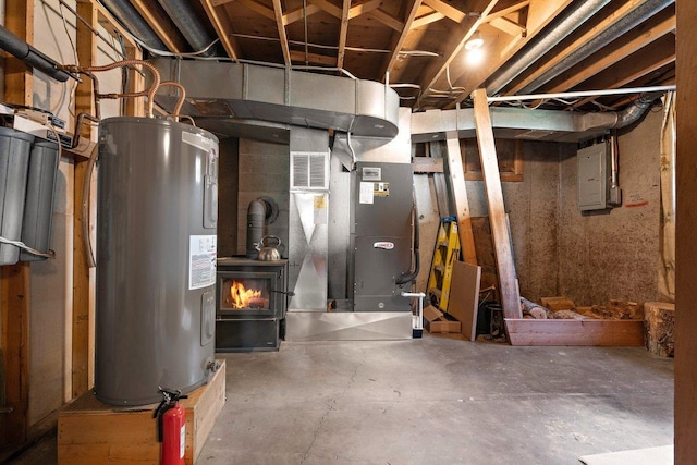 unfinished basement with a wood stove, visible vents, electric panel, electric water heater, and heating unit