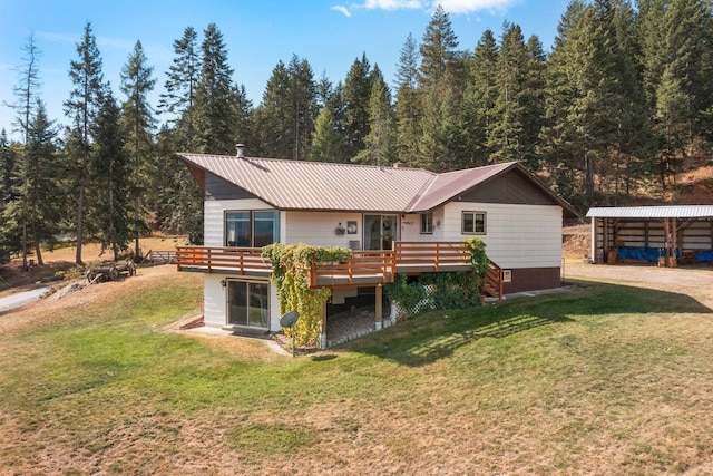 back of house featuring a deck, a lawn, and metal roof