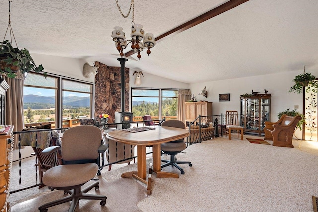 carpeted dining area with a mountain view, an inviting chandelier, lofted ceiling with beams, and a textured ceiling