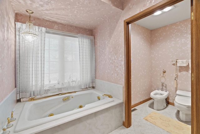 bathroom with toilet, a tub to relax in, an inviting chandelier, and a bidet