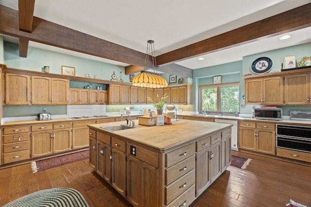 kitchen with dark hardwood / wood-style flooring, sink, pendant lighting, beam ceiling, and a center island with sink