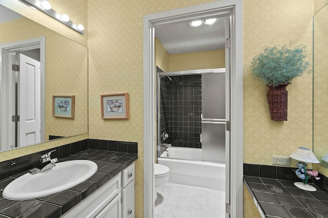 full bathroom with shower / bath combination with glass door, tile patterned flooring, vanity, and toilet