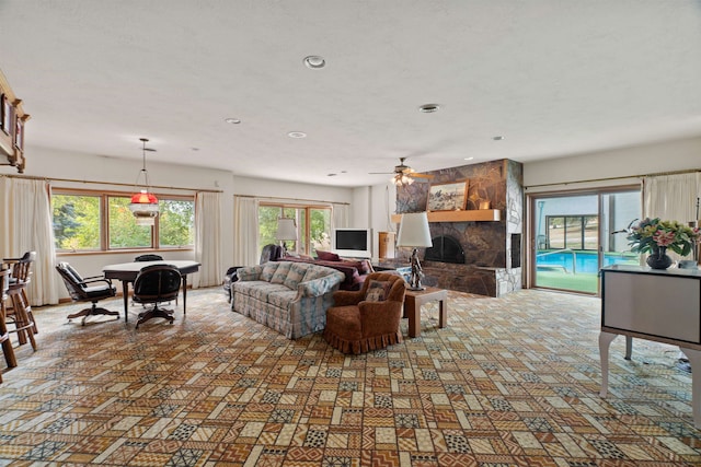 living room with plenty of natural light, ceiling fan, and a stone fireplace