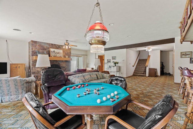 recreation room featuring a stone fireplace and ceiling fan