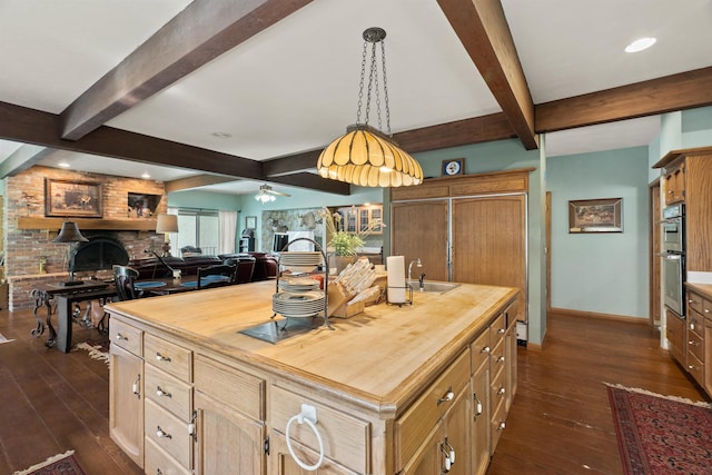 kitchen with butcher block counters, ceiling fan, a kitchen island, and dark wood-type flooring