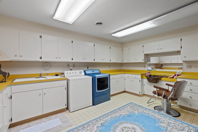 clothes washing area with cabinets, washing machine and dryer, and sink