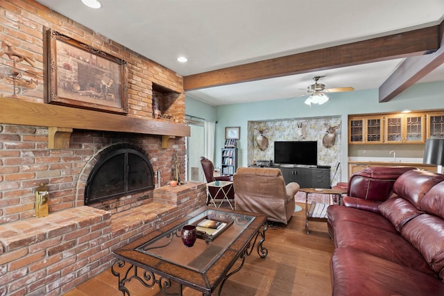 living room with hardwood / wood-style floors, a brick fireplace, ceiling fan, bar, and beamed ceiling