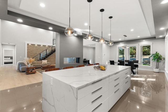 kitchen featuring a spacious island, light tile patterned floors, hanging light fixtures, and white cabinets