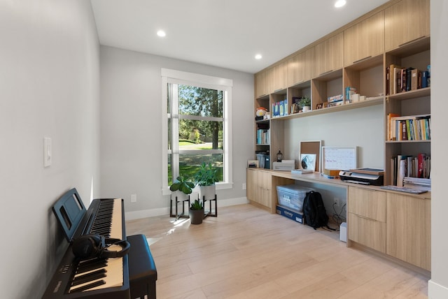 home office with built in desk and light hardwood / wood-style floors