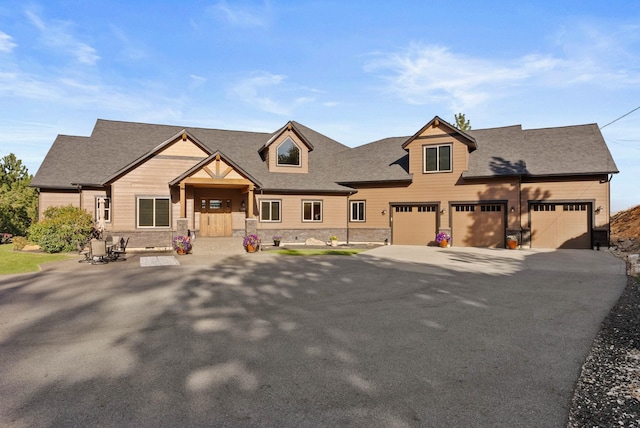 view of front of house with a porch, roof with shingles, stone siding, and aphalt driveway