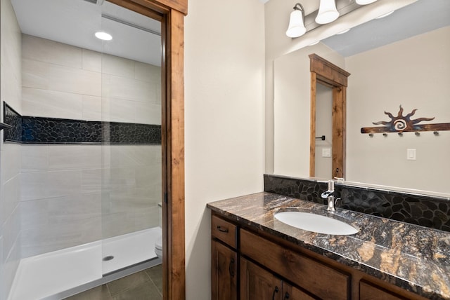 bathroom featuring tiled shower, toilet, tile patterned flooring, and vanity