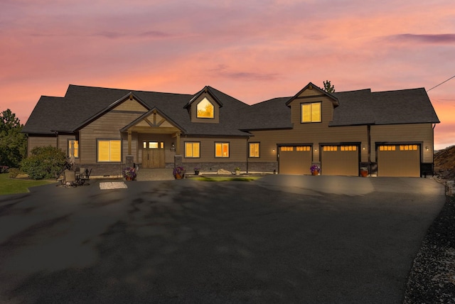 view of front of property featuring a porch, stone siding, a garage, and aphalt driveway