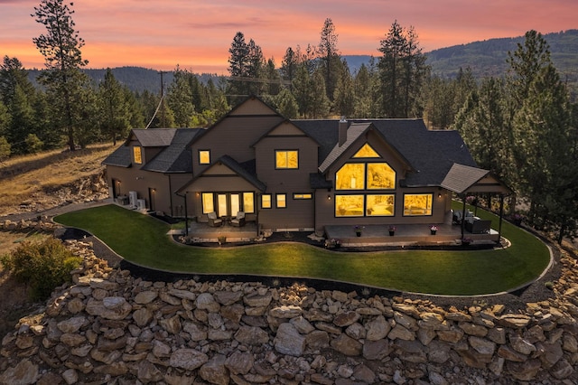 back of house with a patio, a mountain view, a yard, and a wooded view
