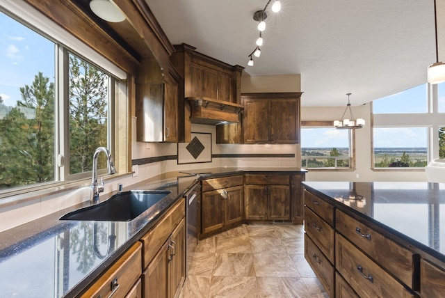 kitchen with dark stone counters, stainless steel dishwasher, a sink, a notable chandelier, and hanging light fixtures