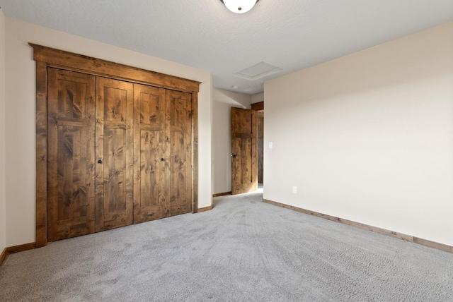 unfurnished bedroom featuring baseboards, attic access, and carpet flooring