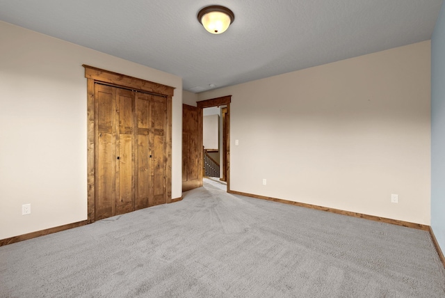 unfurnished bedroom featuring baseboards, carpet floors, and a closet