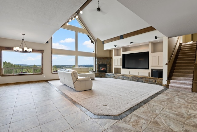 unfurnished living room with track lighting, a notable chandelier, a fireplace, high vaulted ceiling, and light tile patterned floors