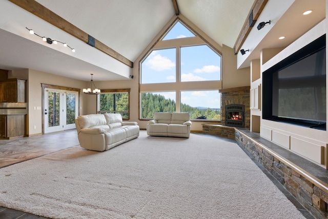 unfurnished living room featuring a notable chandelier, beam ceiling, carpet floors, high vaulted ceiling, and a stone fireplace