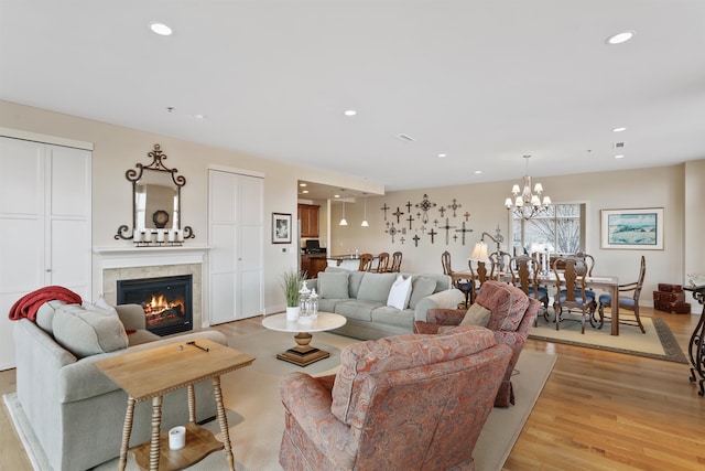 living room featuring light hardwood / wood-style floors, a fireplace, and an inviting chandelier