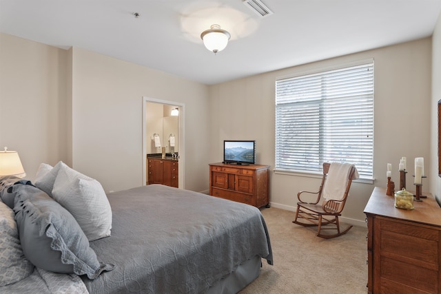 bedroom with ensuite bath and light colored carpet