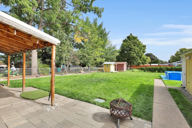 view of yard with a patio area, a storage unit, and an outdoor fire pit