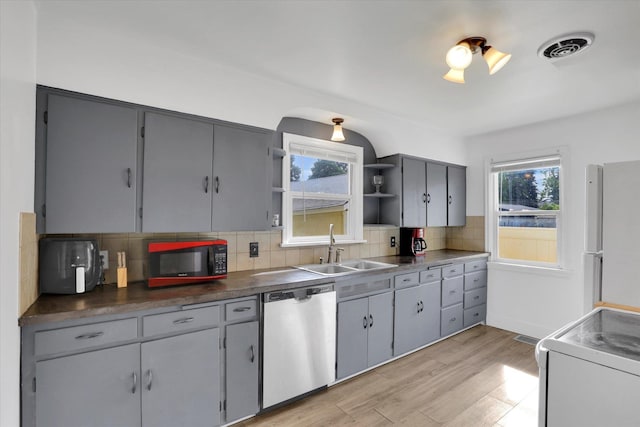 kitchen with gray cabinetry, light hardwood / wood-style floors, white fridge, stainless steel dishwasher, and sink