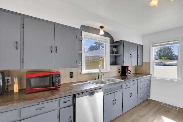 kitchen with a wealth of natural light, dishwasher, light wood-type flooring, and sink