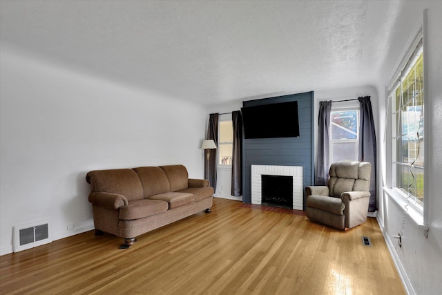 living room with a textured ceiling, a fireplace, and hardwood / wood-style floors