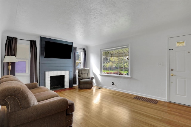 living room with a textured ceiling, a fireplace, and light wood-type flooring