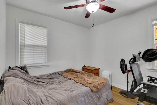 bedroom featuring ceiling fan, multiple windows, and hardwood / wood-style floors