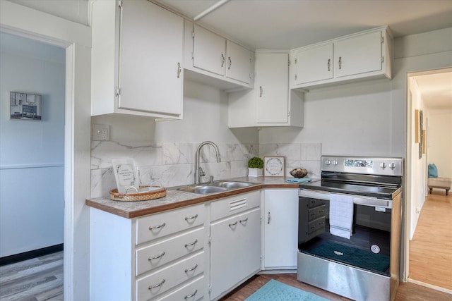 kitchen with light hardwood / wood-style flooring, stainless steel electric range, white cabinetry, and sink