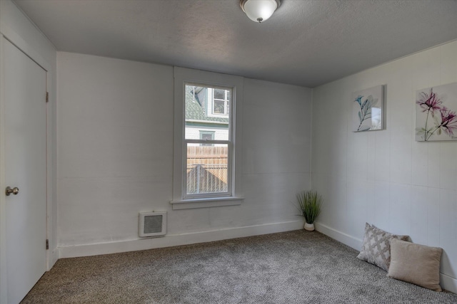 empty room with a textured ceiling and carpet flooring