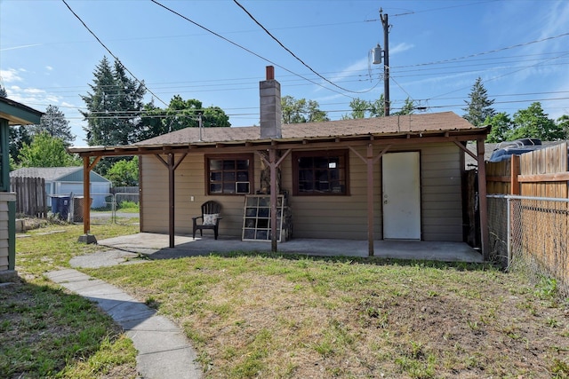 rear view of property with a storage shed, a patio area, and a yard