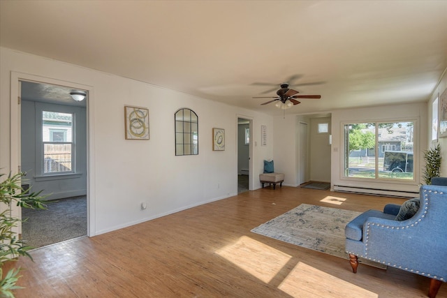 unfurnished living room featuring wood-type flooring, ceiling fan, and baseboard heating