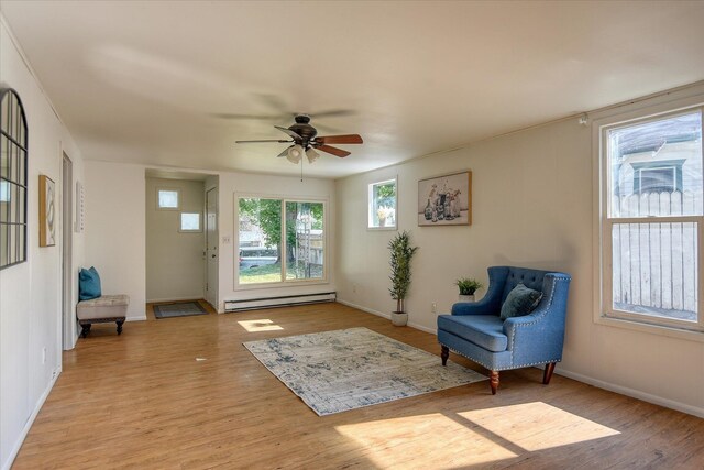 living area with ceiling fan, a baseboard radiator, and light hardwood / wood-style flooring